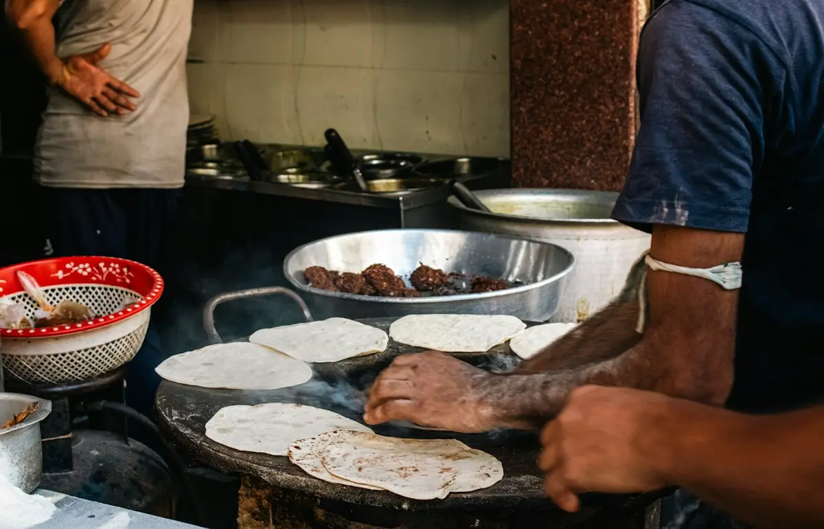 A cook turning rotis on a hot tawa